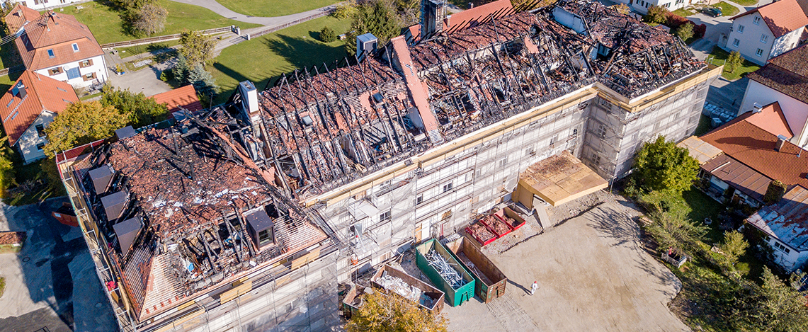 Luftaufnahme von einem großen Haus aus der Entfernung mit abgebranntem Dach