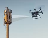 Drohne inspiziert Funkmasten mit blauem Himmel im Hinergrund